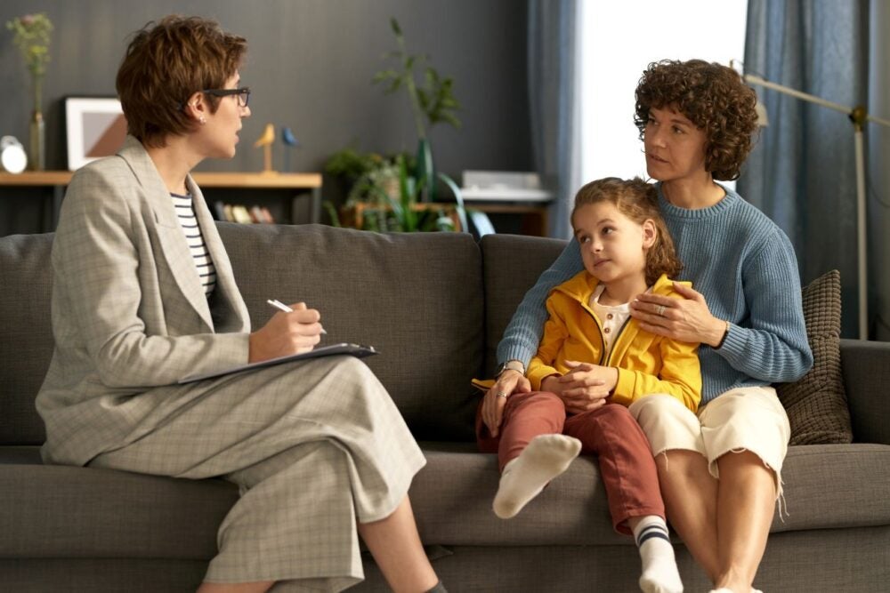 A social services worker speaks with a mother and her child in their home.