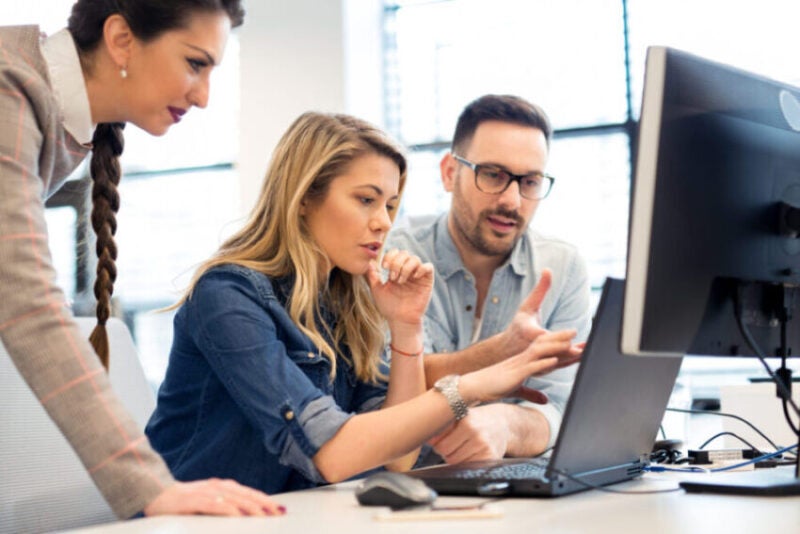 Several people looks at a computer screen.