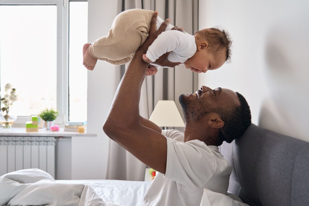 A dad smiles as he holds his baby above his face.