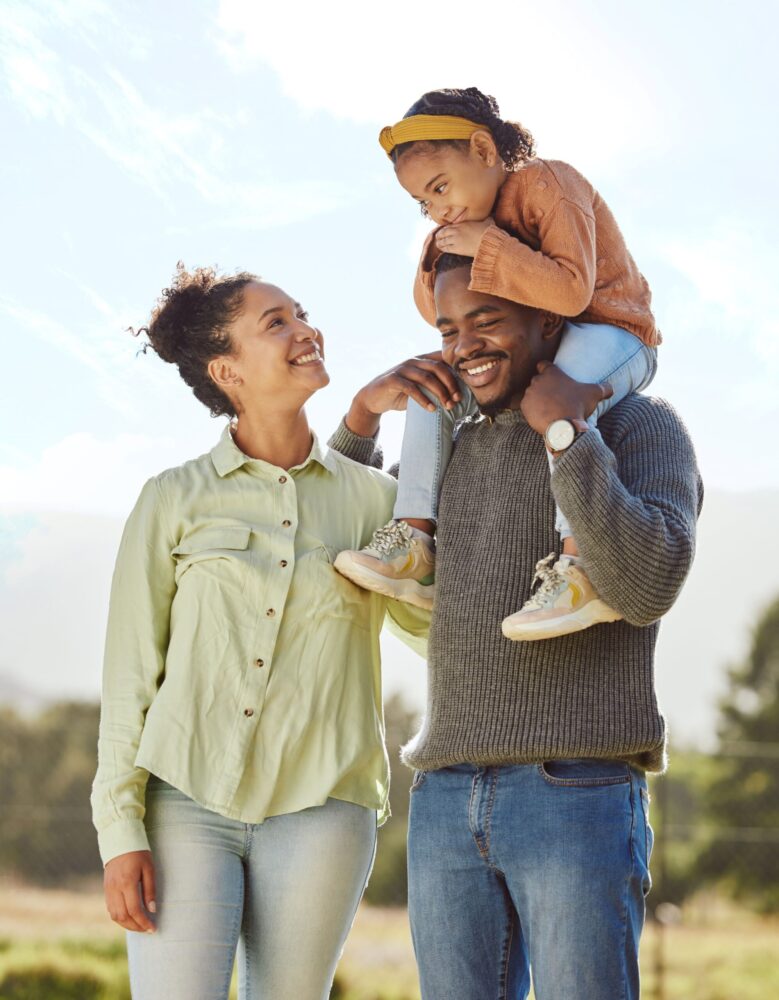 A family is on a walk, the dad carrying his daughter on his shoulders.