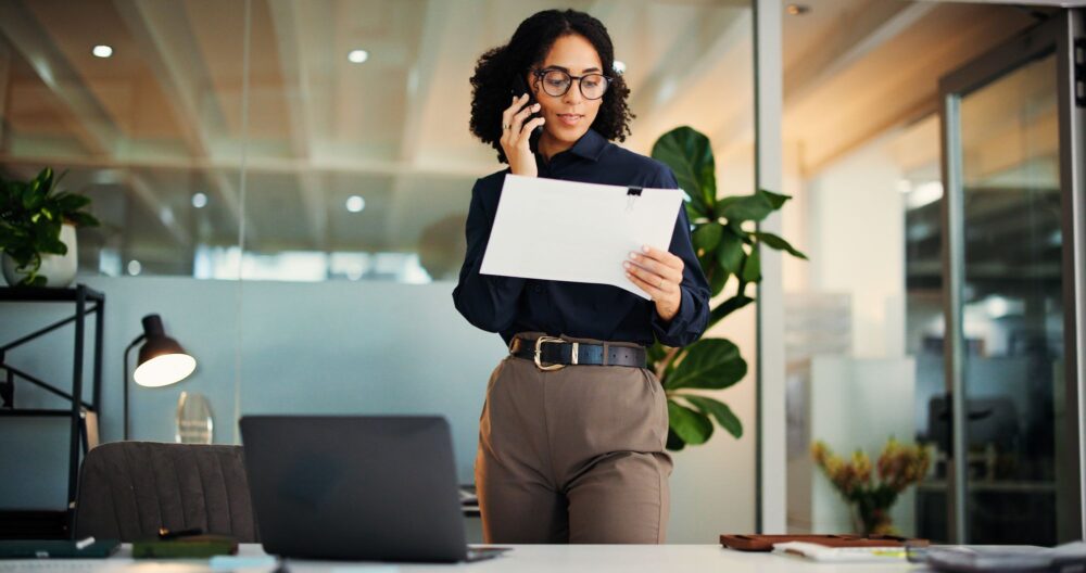 Woman talking on the phone in an office, holding some papers