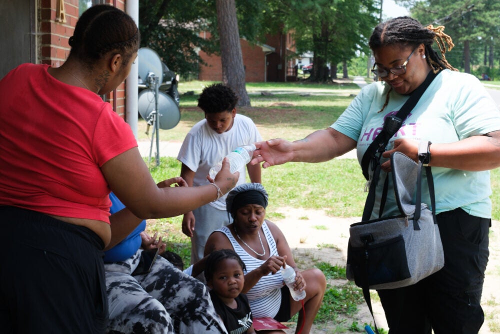 Community health responder passing out supplies in a residential area during a heatwave.