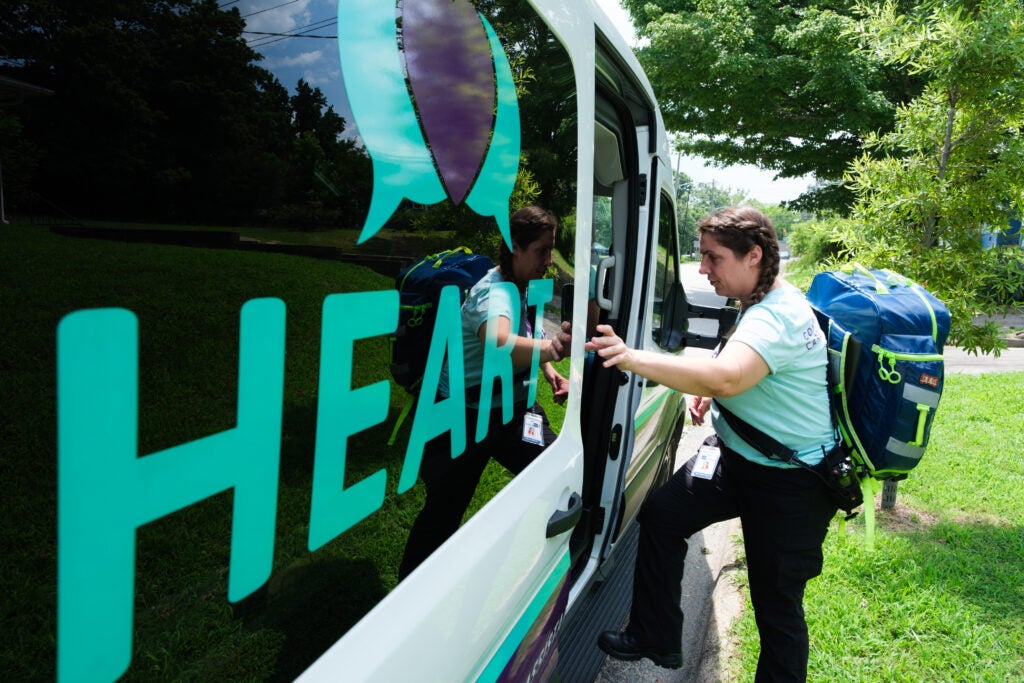 Woman climbs into a van with the name "HEART" written on the side.