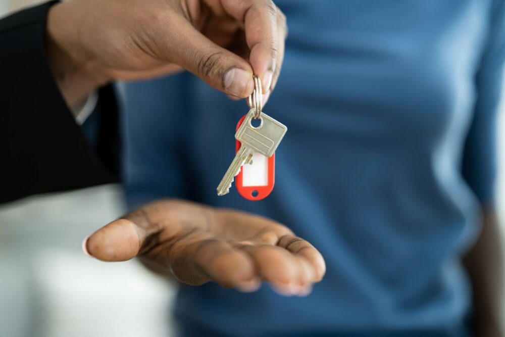 Hand passing a set of house keys to an open palm.