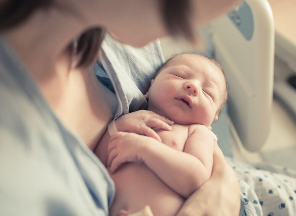 A mother holds her baby in the hospital after giving birth.